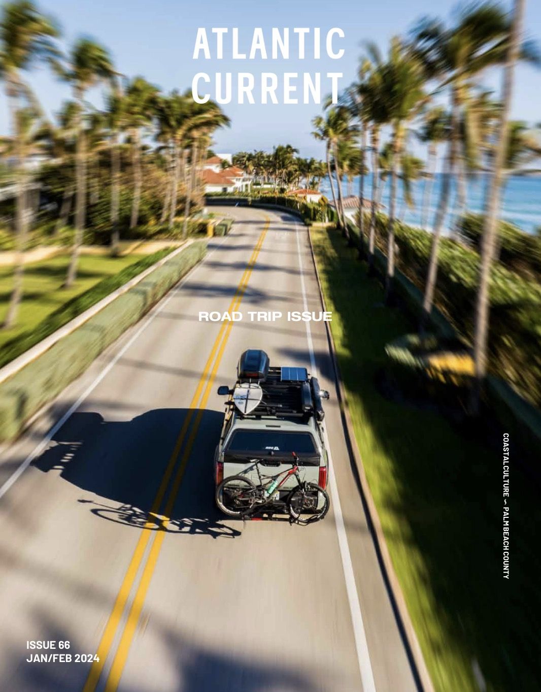 Atlantic Current magazine cover, Issue 66, January/February 2024, the Road Trip Issue: an aerial of a truck carrying a surfboard and a bike down a palm-lined coastal road
