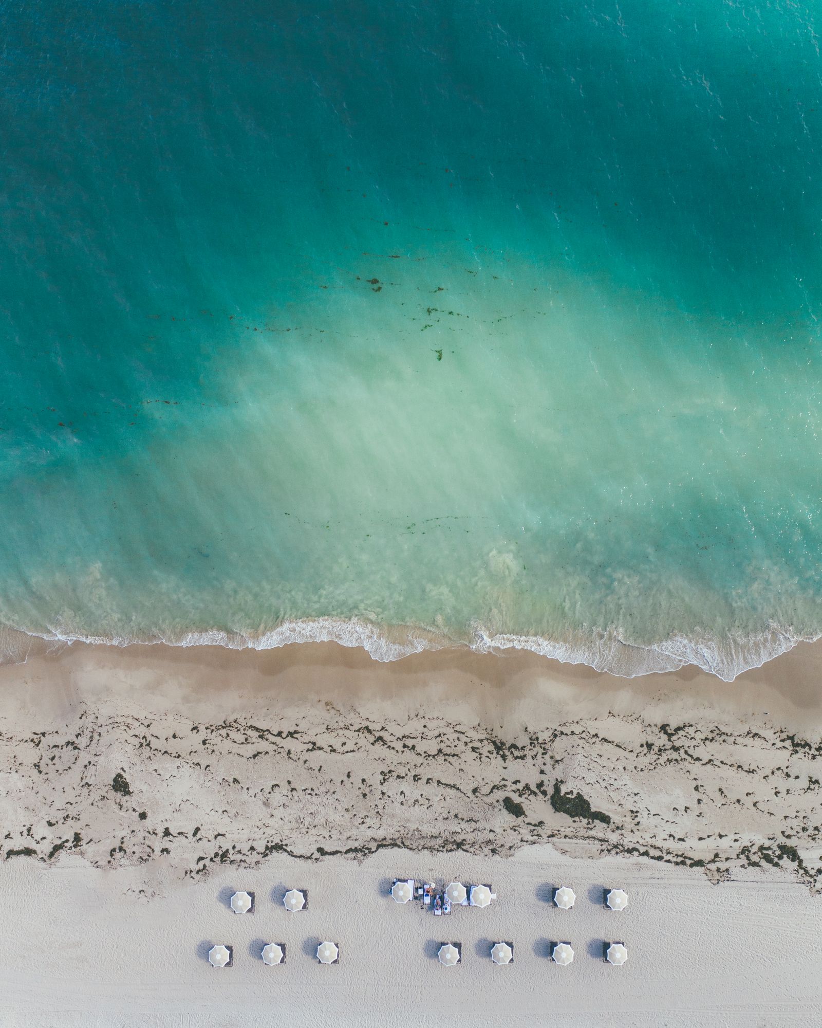 Rows of beach chairs and umbrellas where turquoise water meets white sand