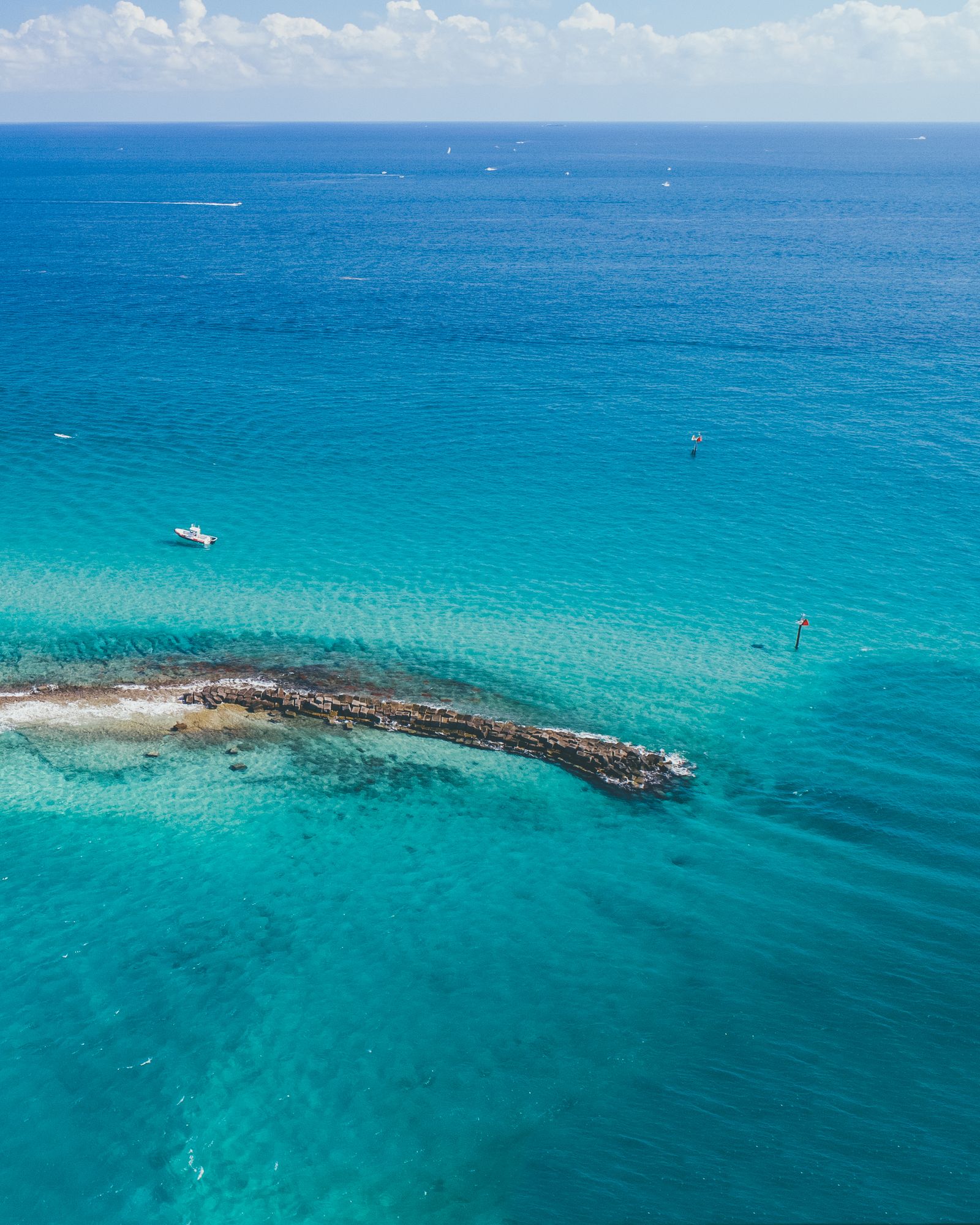 A small island and reef surrounded by deep blue and turquoise water