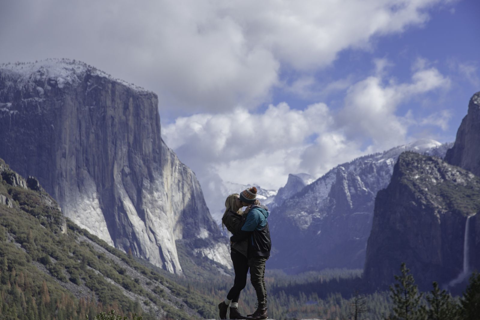 A couple embracing on a rock with El Capitan and Yosemite Valley behind them