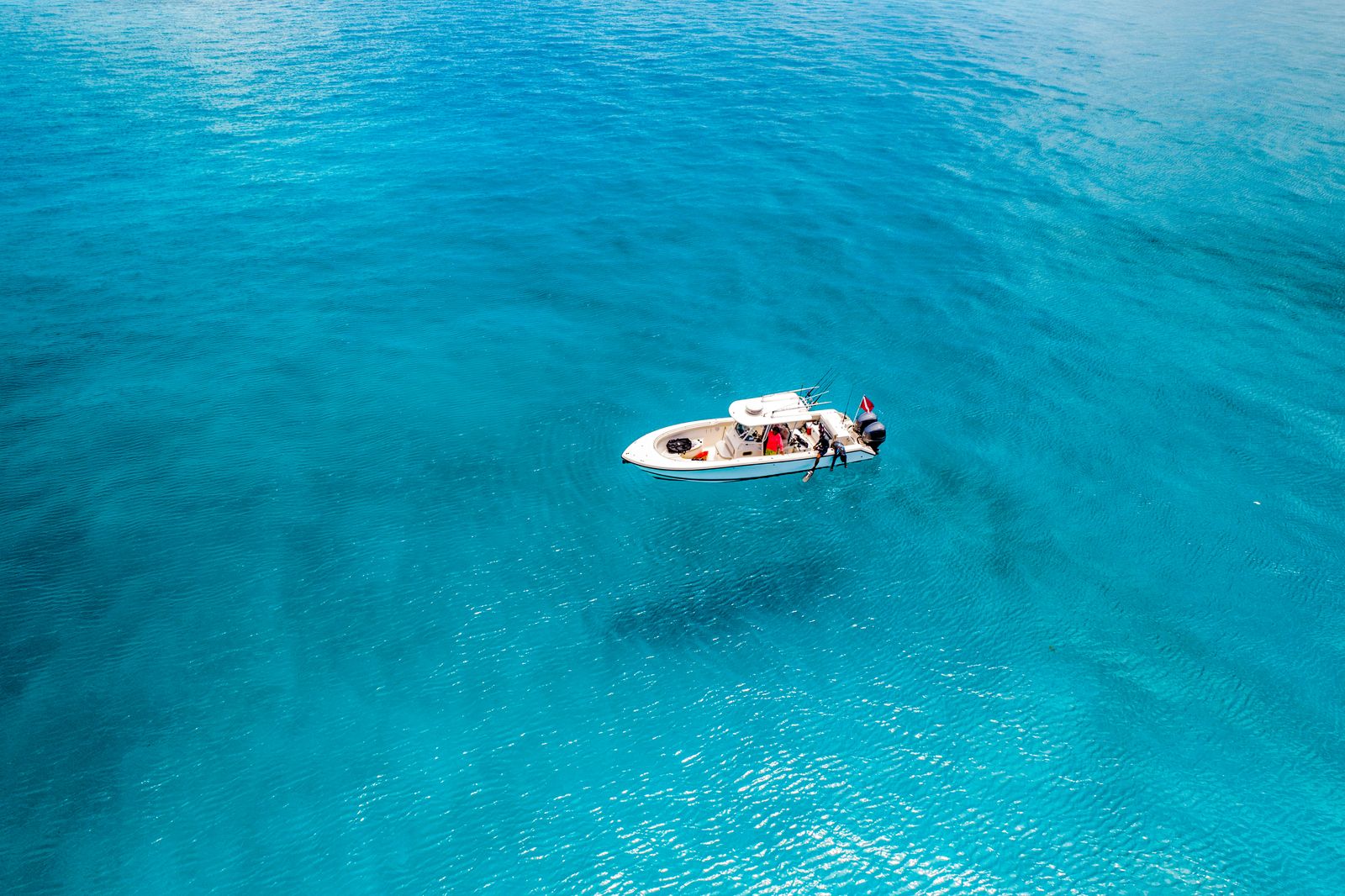 A white boat floating over water so clear it seems to hover above the bottom
