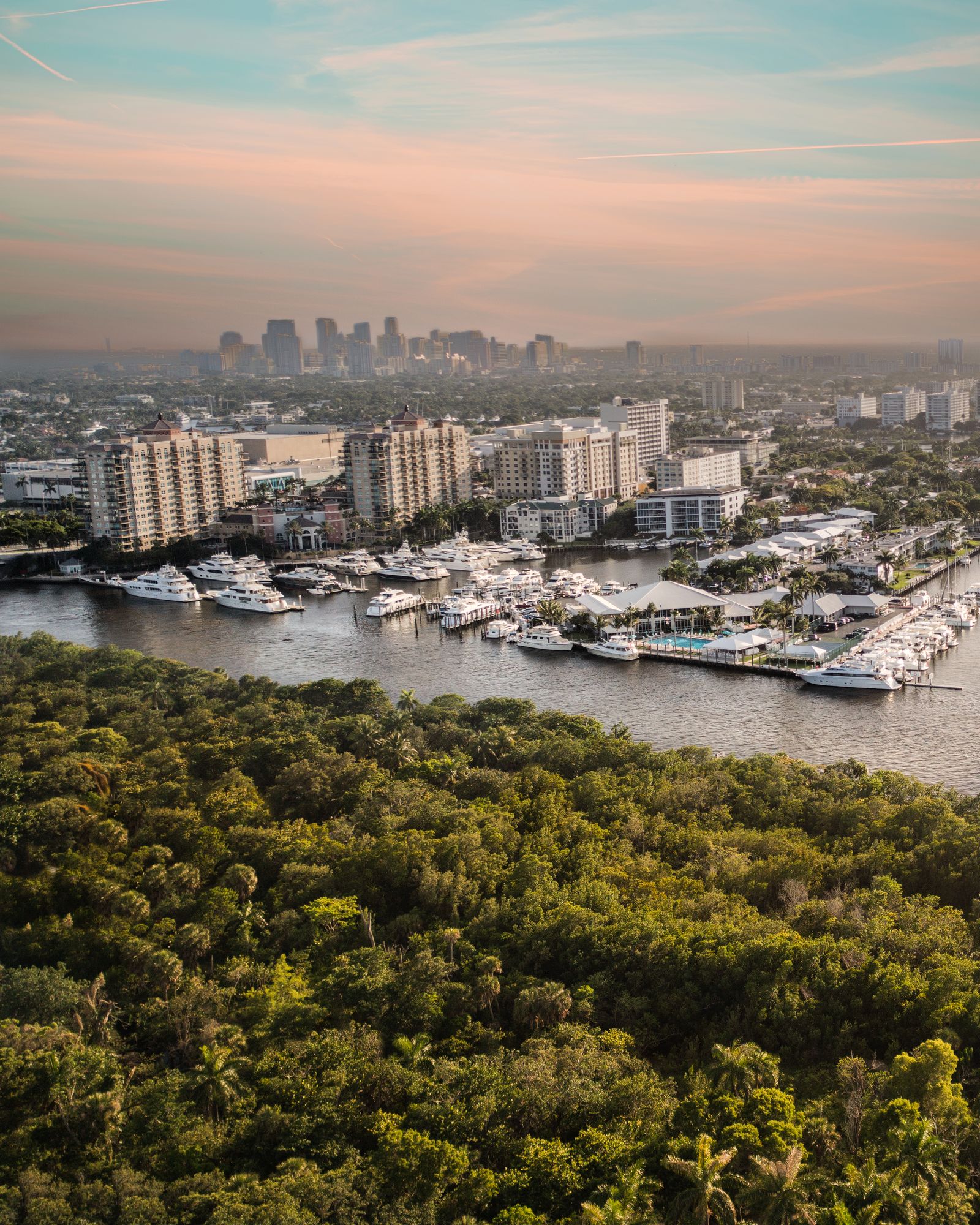 Aerial at sunset over mangroves and a marina toward the downtown Fort Lauderdale skyline