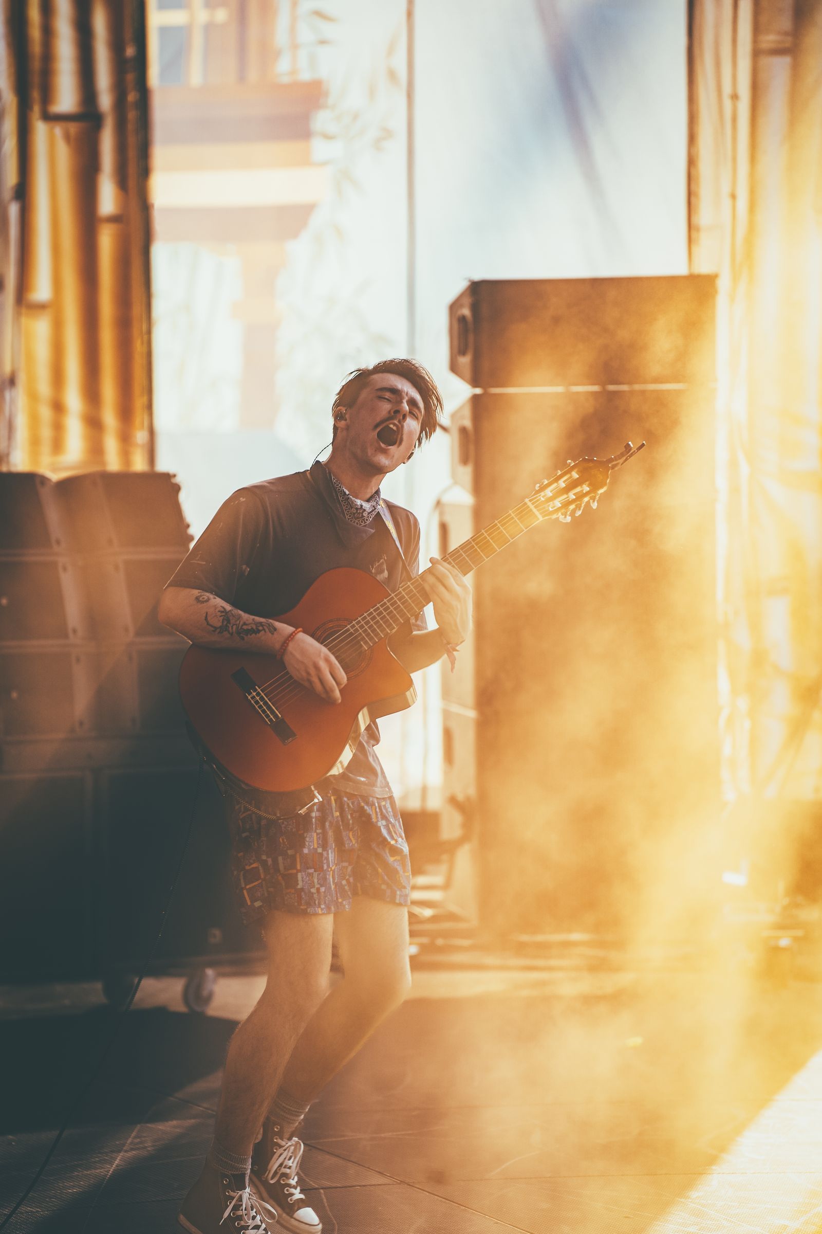 A guitarist playing in warm golden backlight on a smoky stage