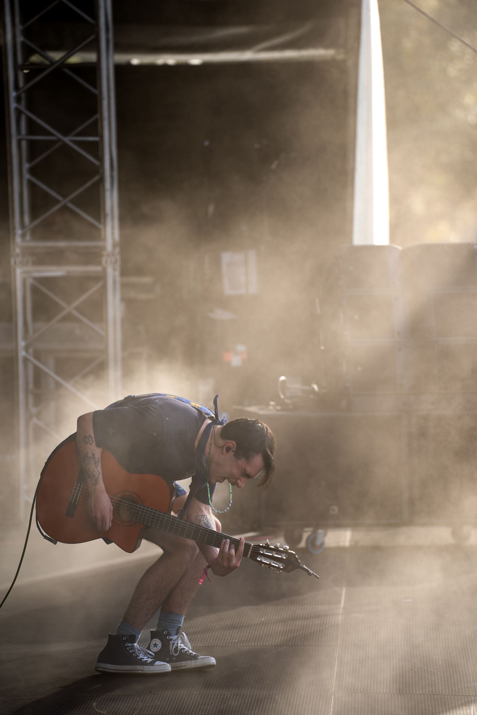 Goth Babe bent over his guitar in stage haze and backlight