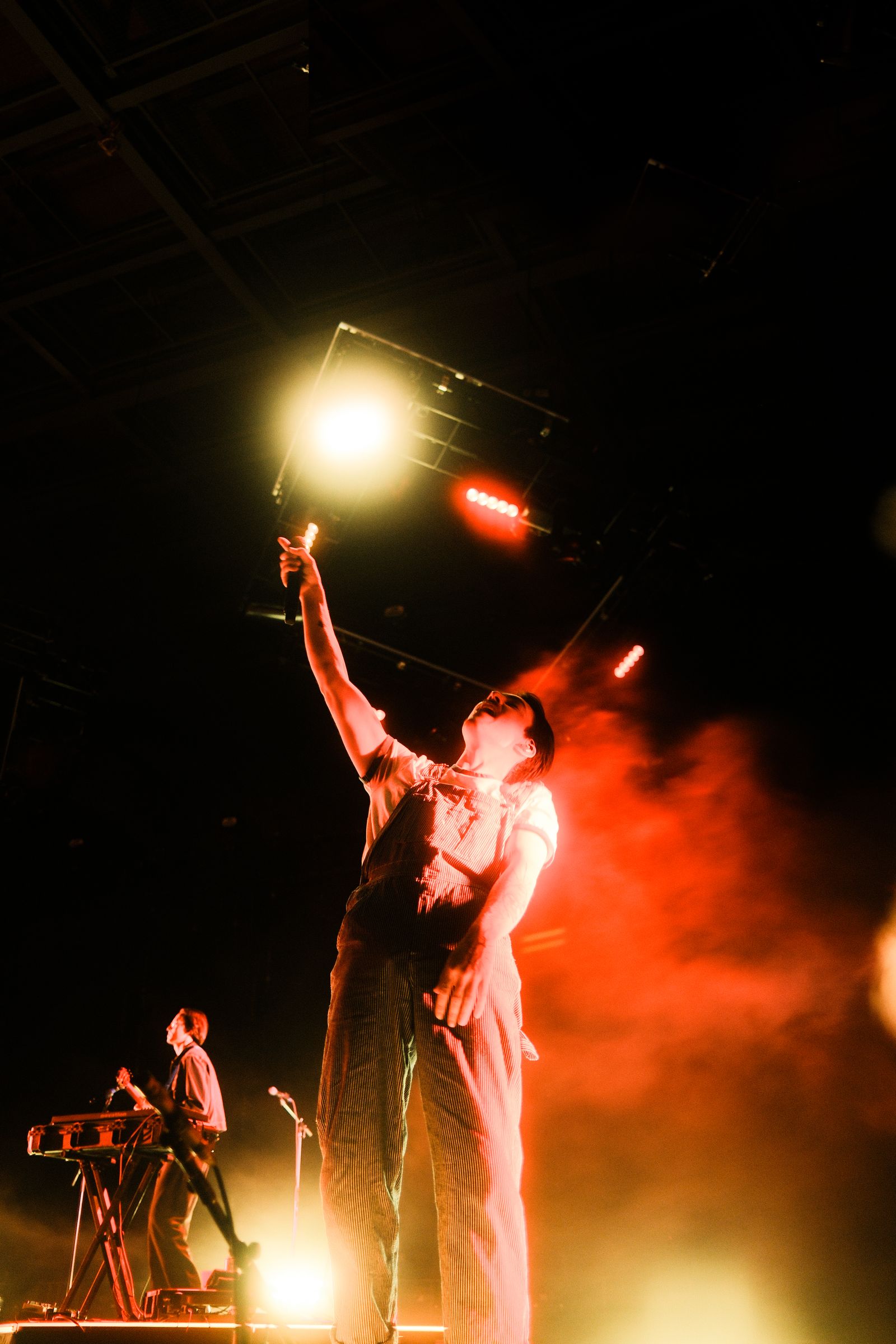 Goth Babe reaching toward a bright stage light at Red Rocks, red smoke behind him