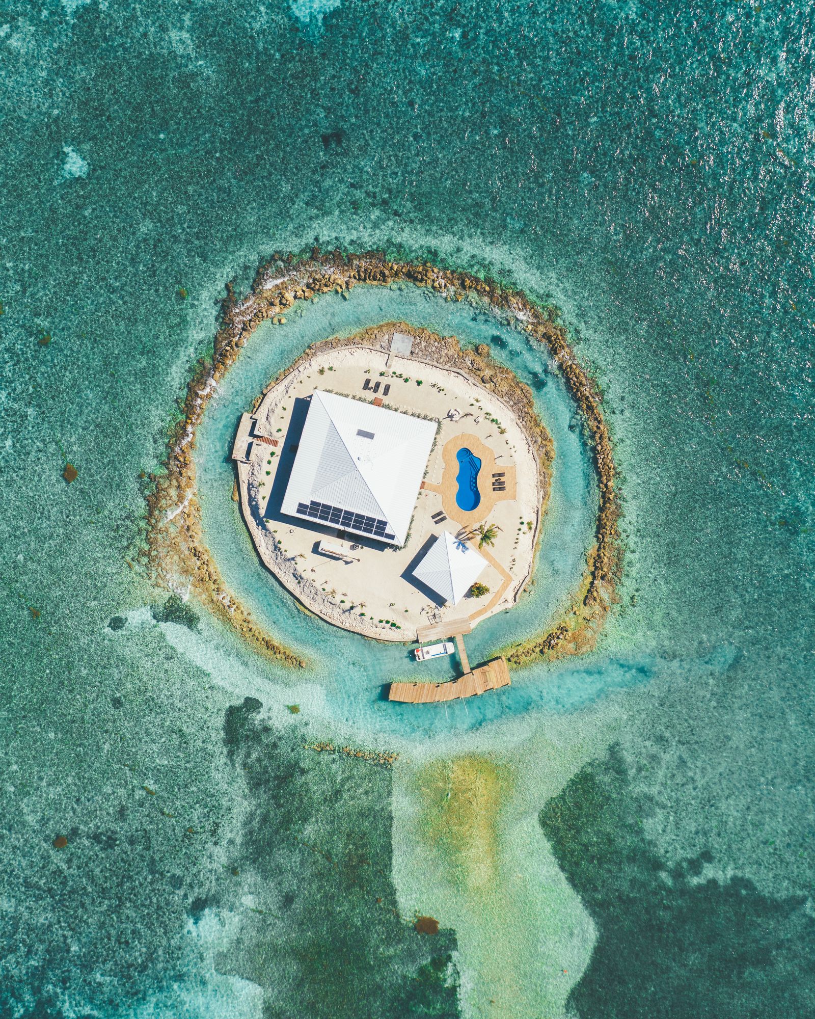 Aerial of a single house on a tiny round island ringed by sand in the Florida Keys