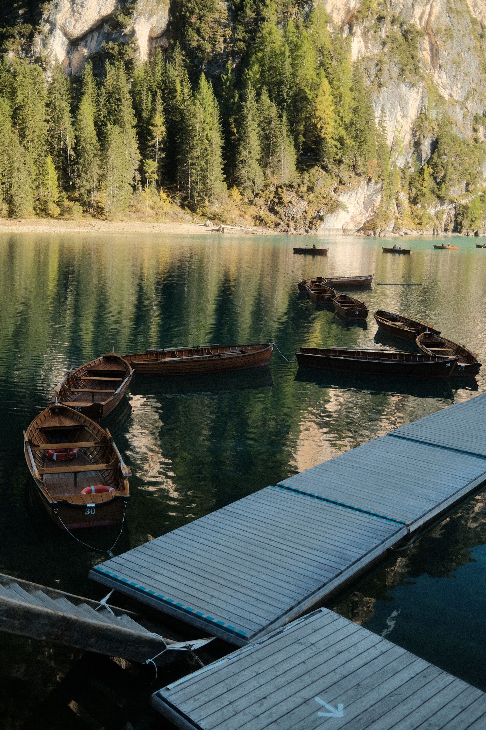 Wooden rowboats moored at a dock on the still green water of Lake Braies