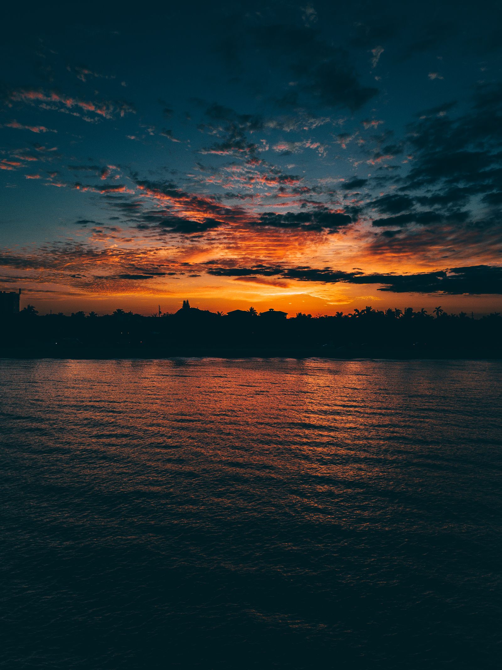 A fiery sunset sky over a dark Fort Lauderdale skyline and still water