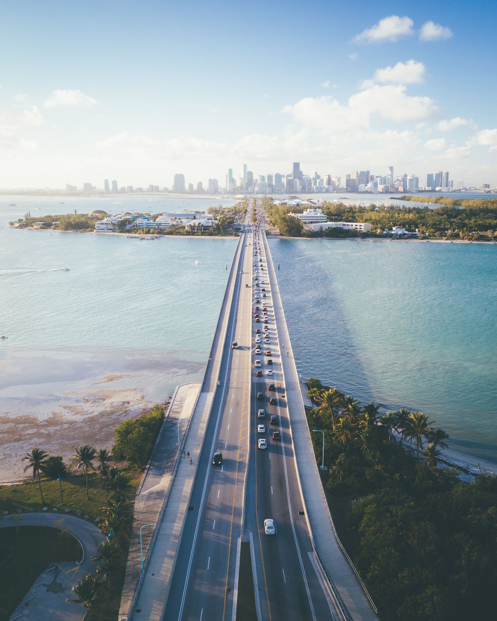 A causeway bridge leading across the bay toward the Miami skyline on a clear day
