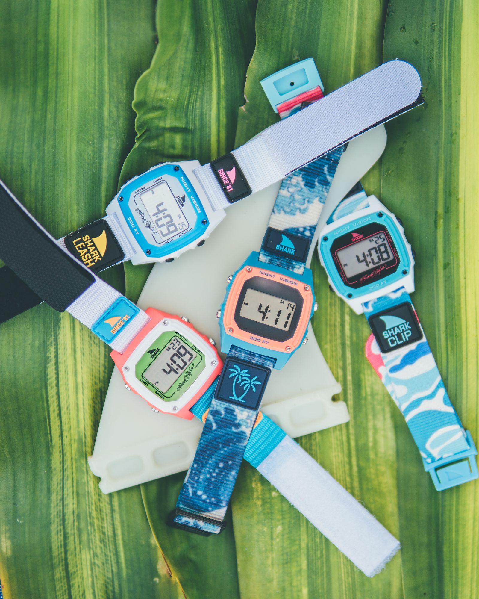 A spread of colorful Freestyle watches and straps on a green palm frond