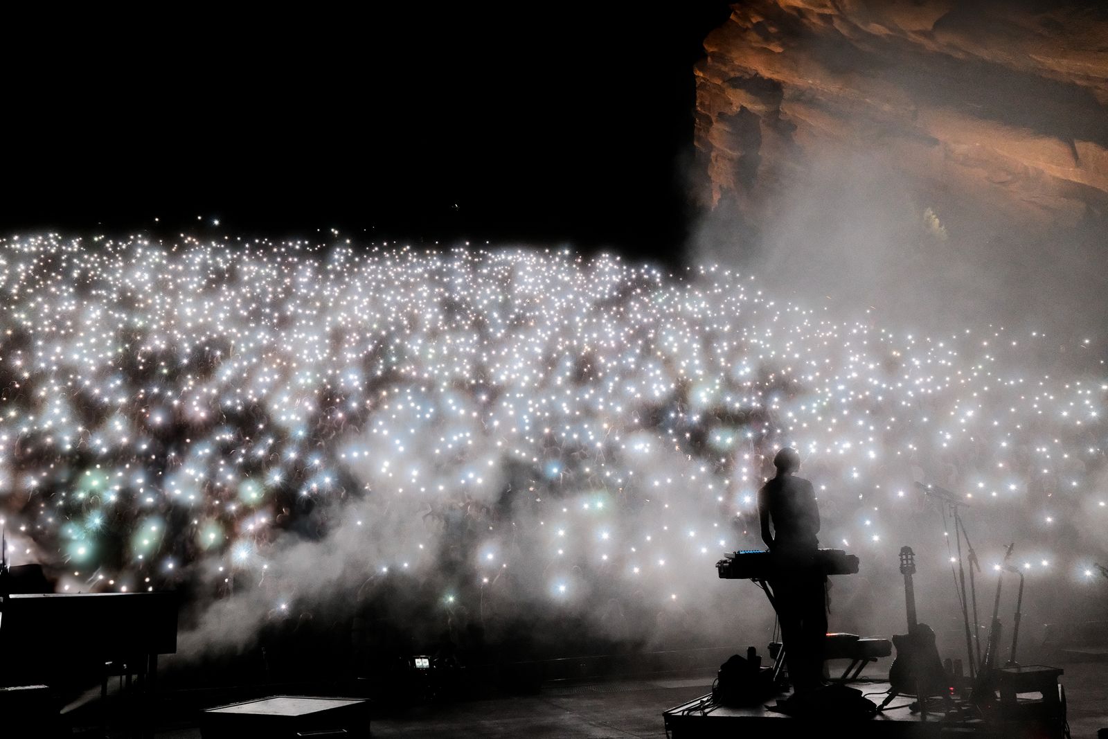 Thousands of phone lights filling the Red Rocks crowd behind a silhouetted keyboard player