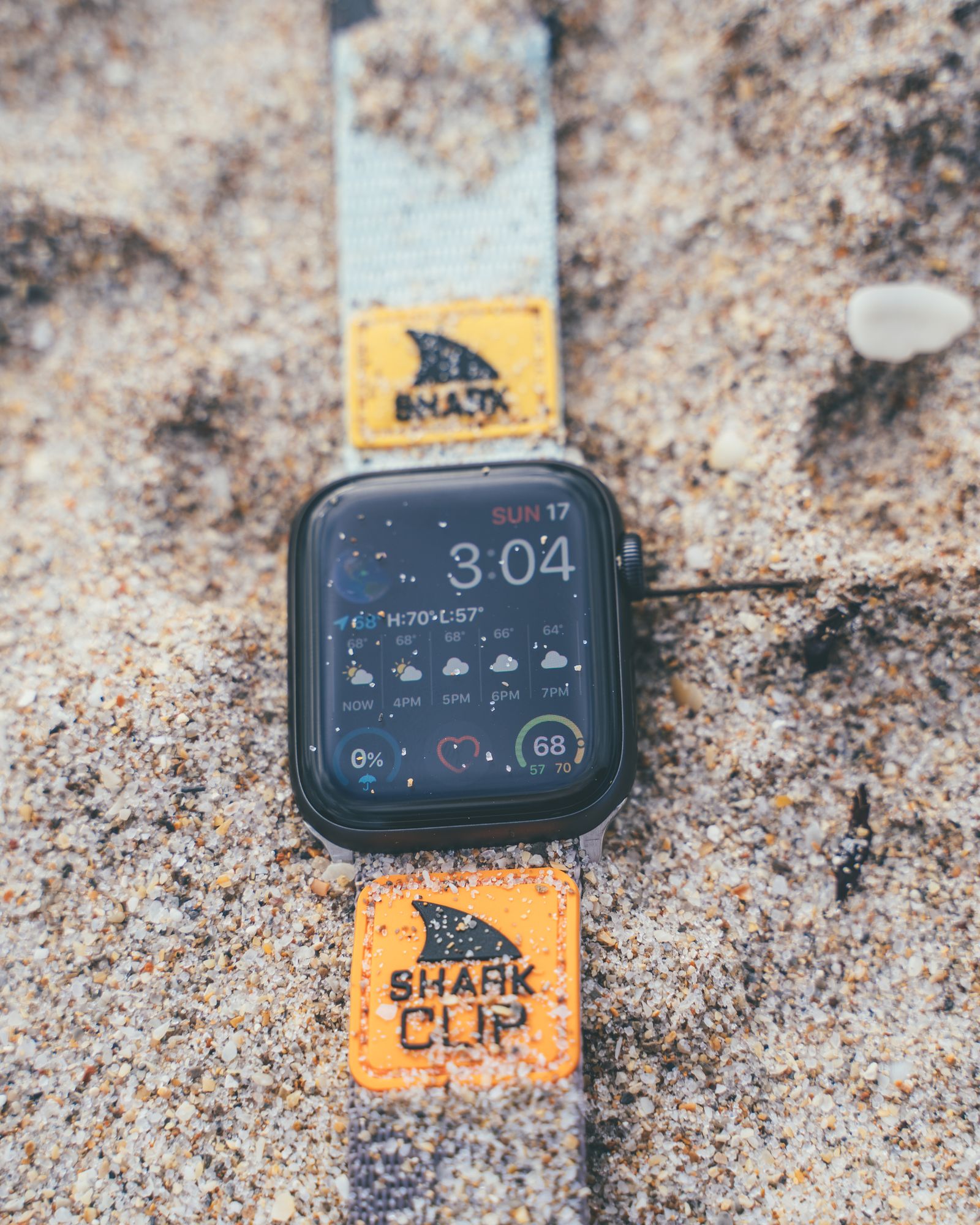 A smartwatch on a Freestyle Shark strap lying in coarse sand