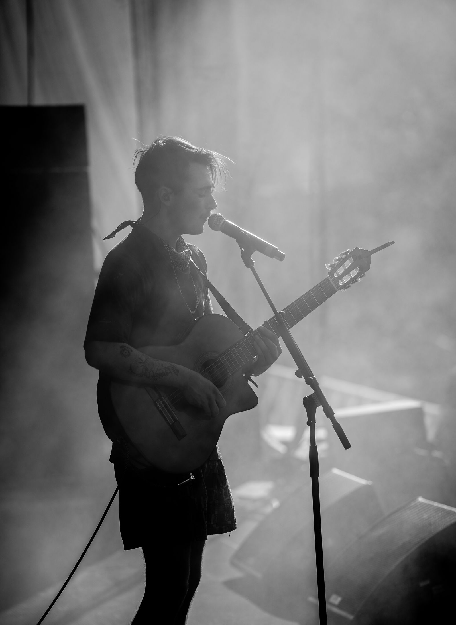 A black and white photo of a singer and guitarist backlit on stage