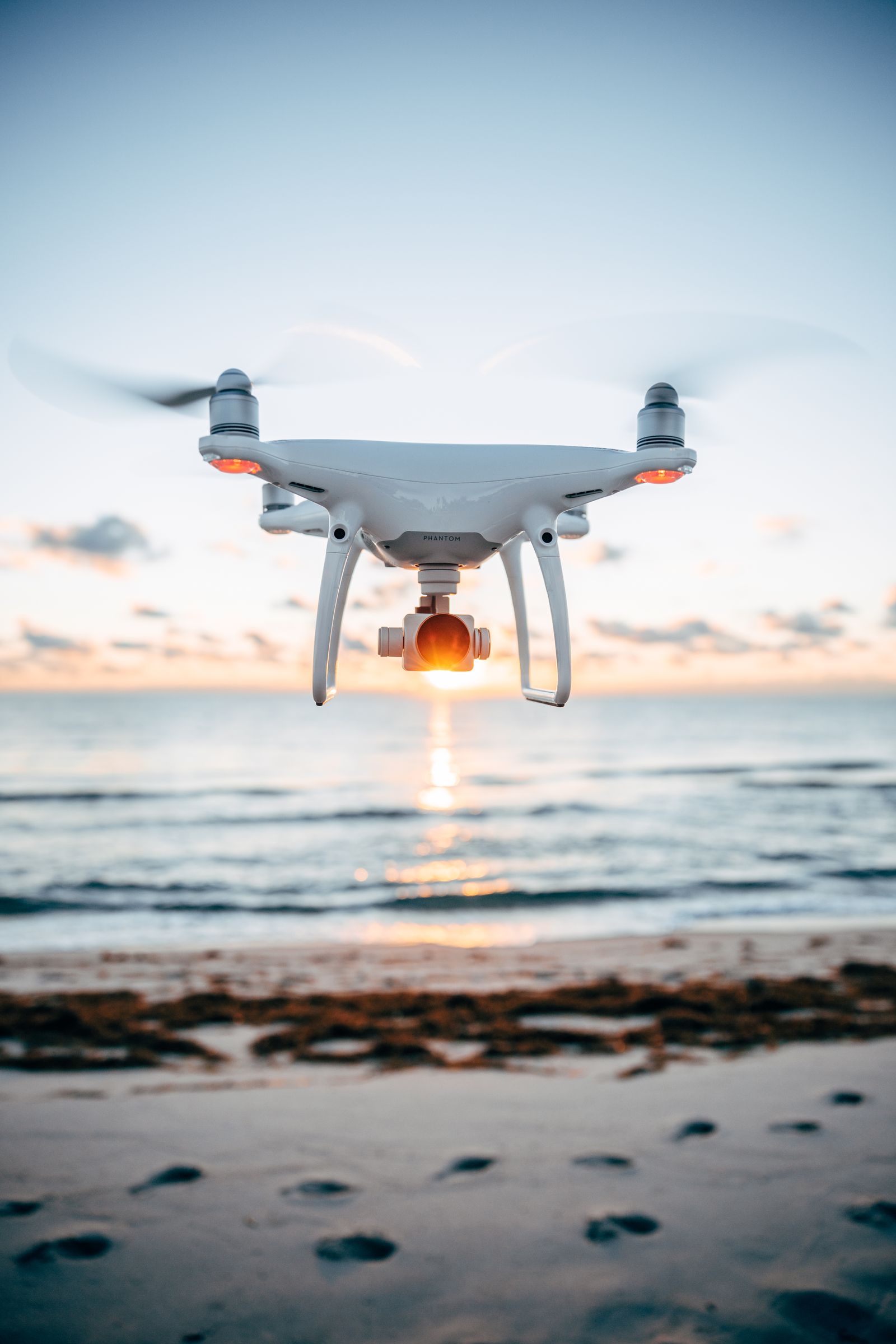 A DJI Phantom with PolarPro filters hovering over the sand at sunset