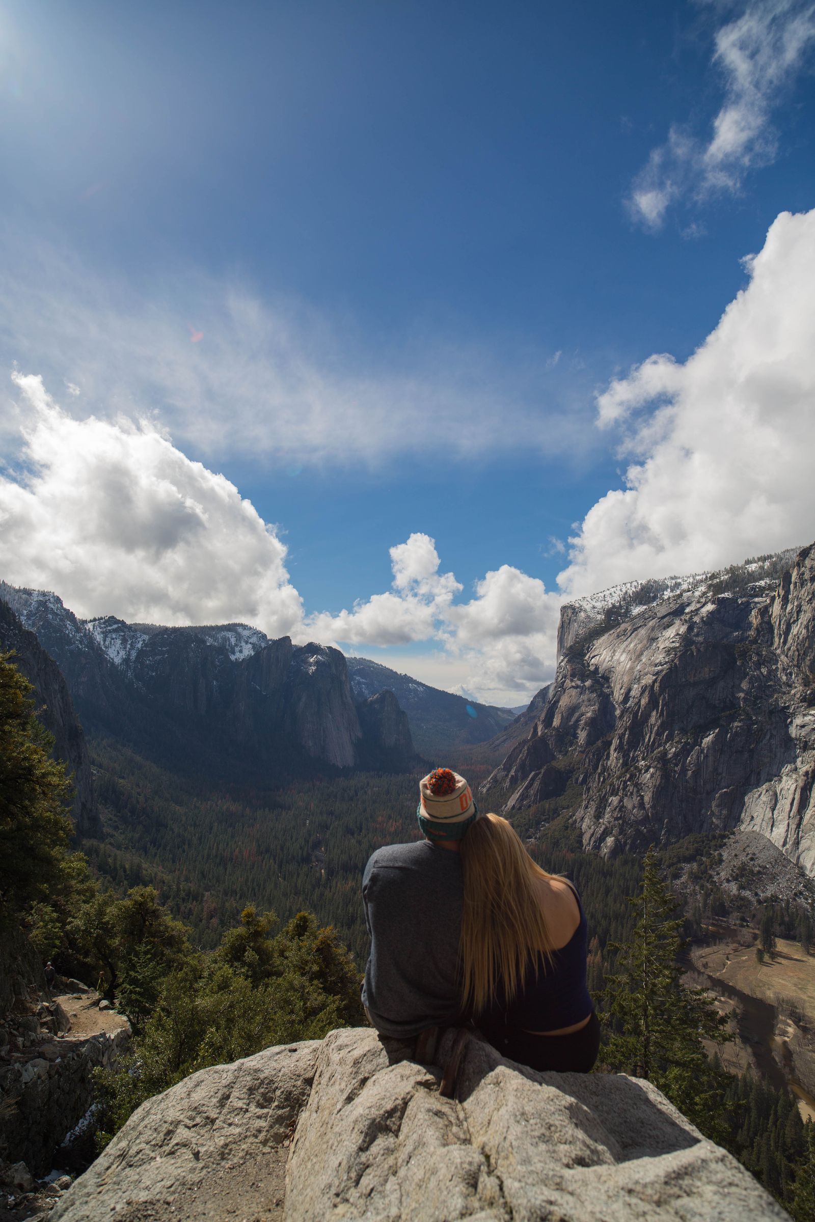 A woman sitting on a granite ledge looking out over Yosemite Valley