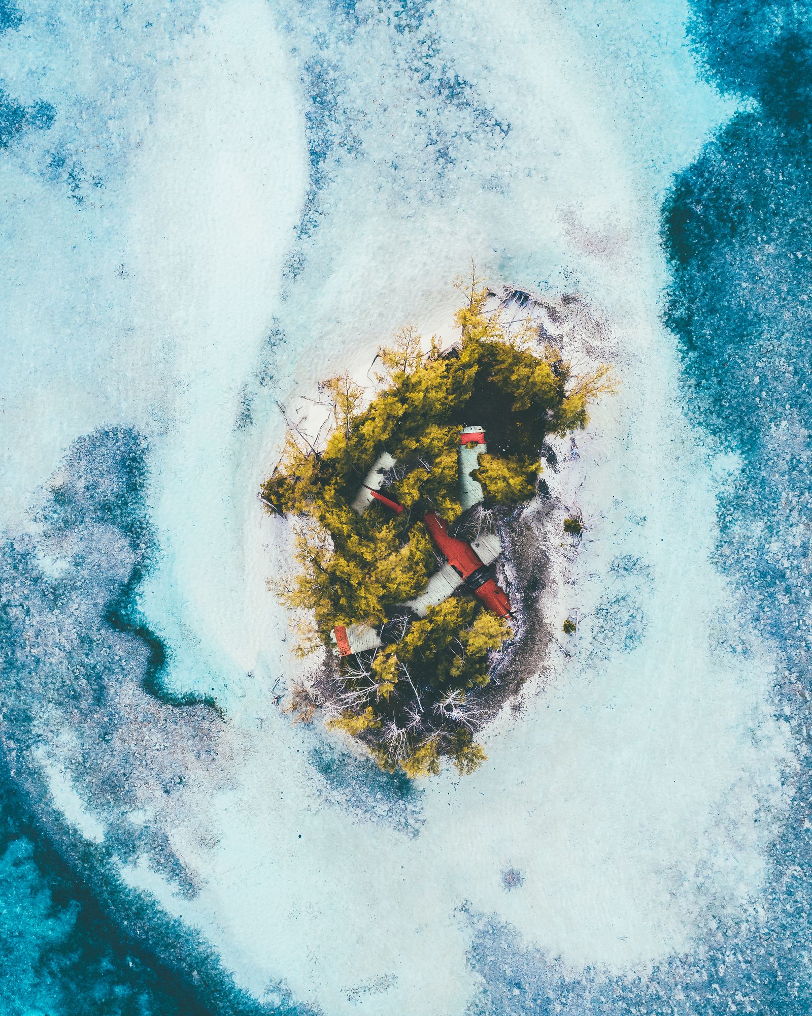 A small island ringed by white surf and deep blue water with a plane wreck on its shore, from directly above